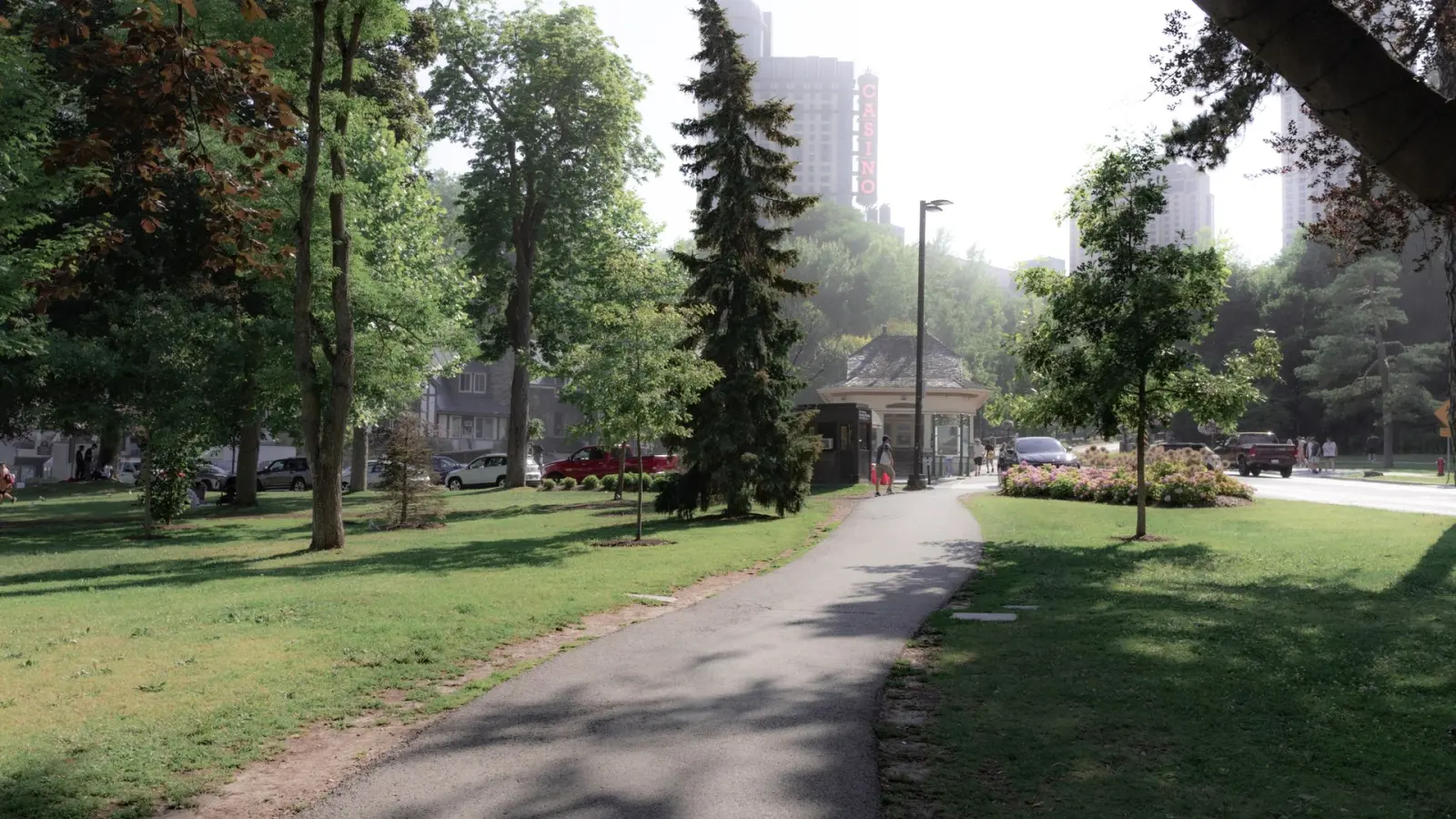 Public park walkway between maintained lawns and trees, representing public-sector grounds care.