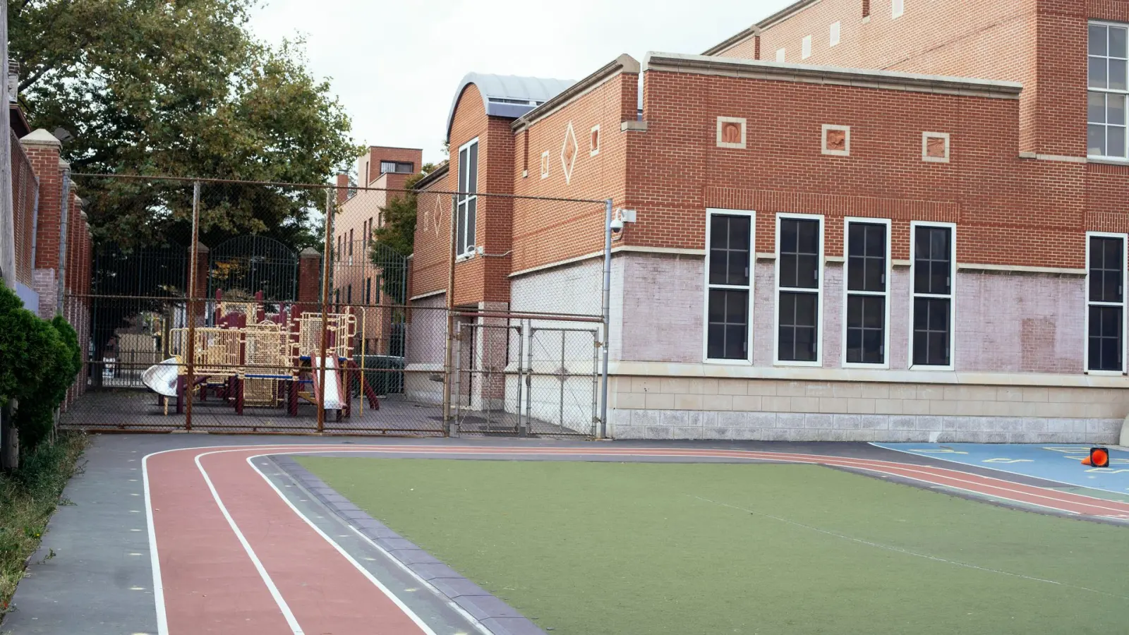 Edificio escolar junto a una cancha vacía, un plantel típico para cuidado orgánico y MIP.